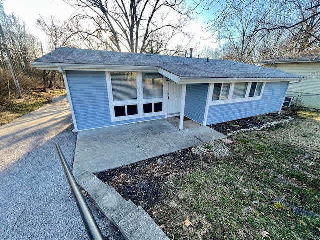 view of front of house featuring a shingled roof and a patio