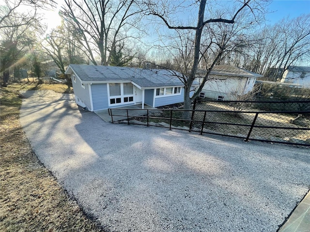 bungalow featuring fence, driveway, and a shingled roof