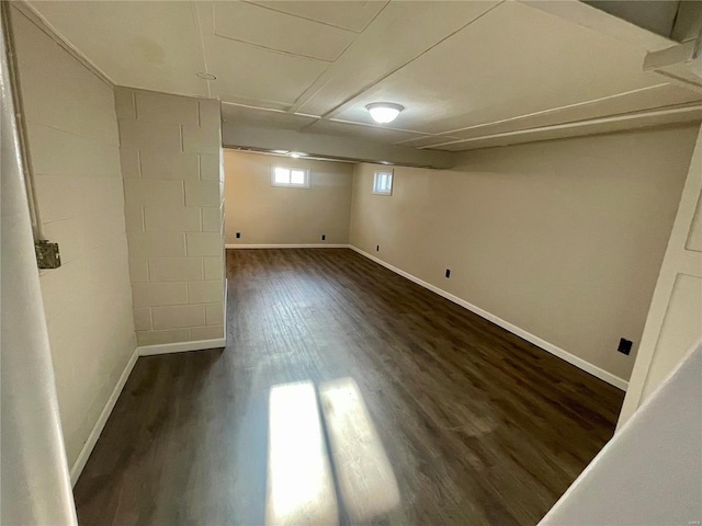 basement featuring baseboards and dark wood-style flooring