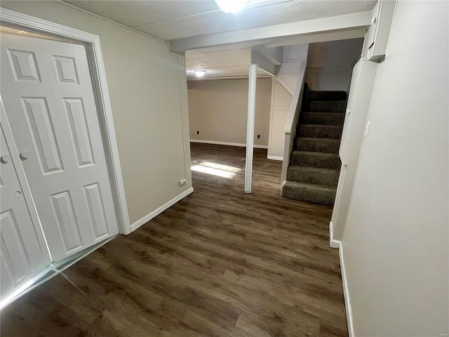 finished basement featuring stairs, dark wood-type flooring, and baseboards