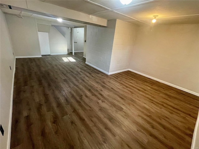 finished basement with baseboards, concrete block wall, and dark wood-style flooring