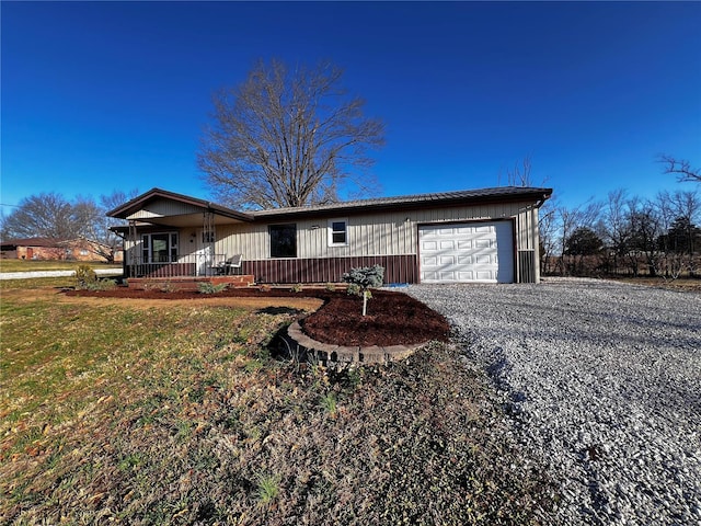 single story home featuring gravel driveway, a porch, a garage, and a front yard