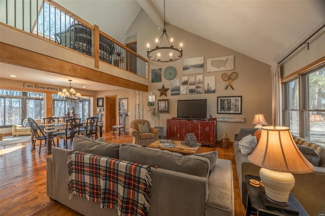 living area with high vaulted ceiling, an inviting chandelier, wood finished floors, and a healthy amount of sunlight