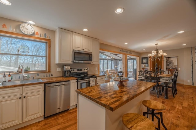 kitchen with a sink, stainless steel appliances, light wood-type flooring, and butcher block countertops