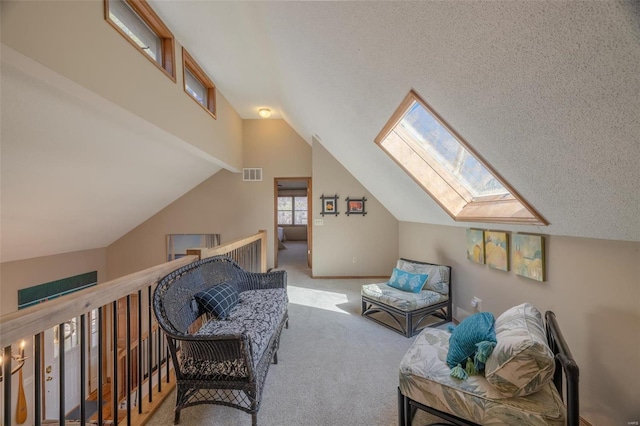 living area featuring visible vents, a textured ceiling, vaulted ceiling with skylight, carpet, and baseboards