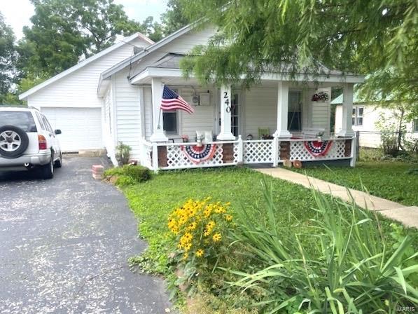 bungalow-style home featuring a porch, an attached garage, and a front lawn