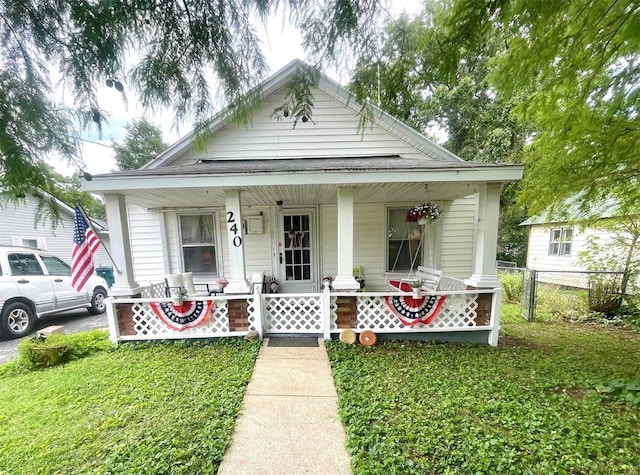 bungalow-style house featuring a front yard, fence, and covered porch