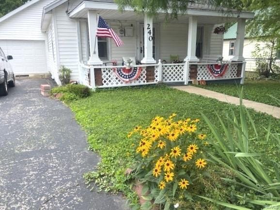 exterior space featuring a porch, a front yard, and aphalt driveway