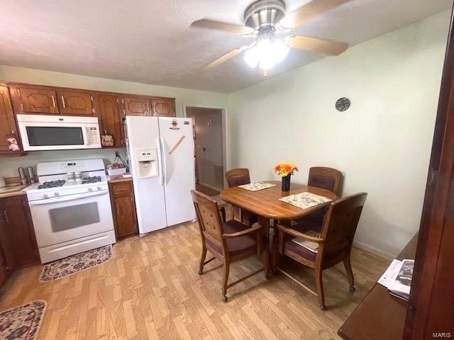 kitchen featuring white appliances, a ceiling fan, brown cabinetry, light countertops, and light wood-type flooring