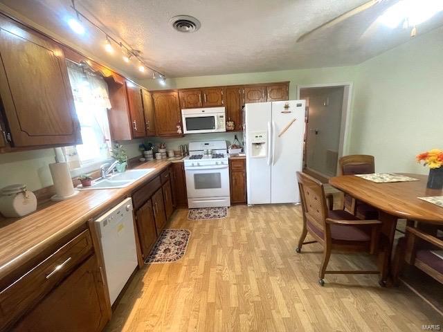 kitchen with white appliances, visible vents, a sink, light countertops, and light wood-type flooring