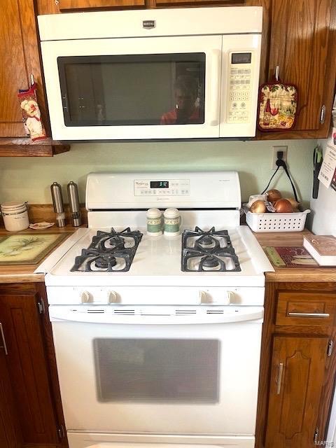 interior space featuring white appliances, brown cabinetry, and light countertops