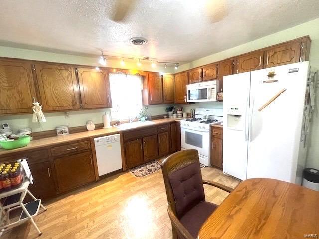 kitchen with visible vents, light countertops, light wood-style flooring, white appliances, and a textured ceiling