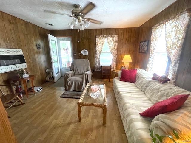 living room with wooden walls, a textured ceiling, and wood finished floors