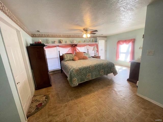 bedroom featuring baseboards, a textured ceiling, and ceiling fan