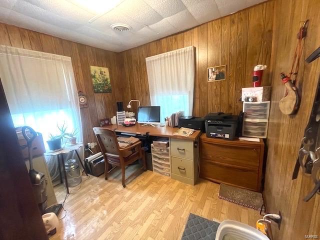 office area featuring visible vents, wood walls, and light wood finished floors