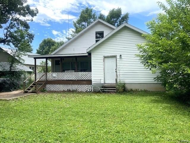 rear view of property with a lawn, entry steps, and a sunroom