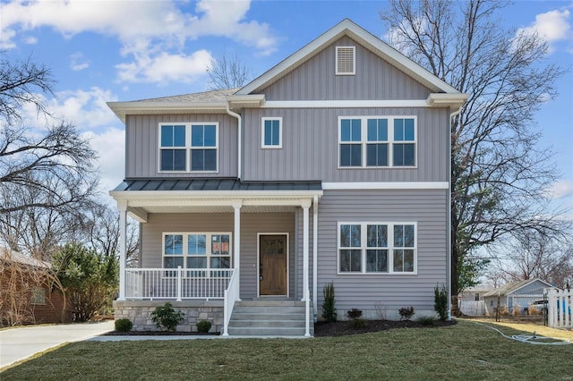 craftsman-style house with board and batten siding, a front yard, covered porch, metal roof, and a standing seam roof