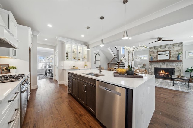 kitchen featuring dark wood finished floors, open floor plan, a fireplace, stainless steel appliances, and a sink