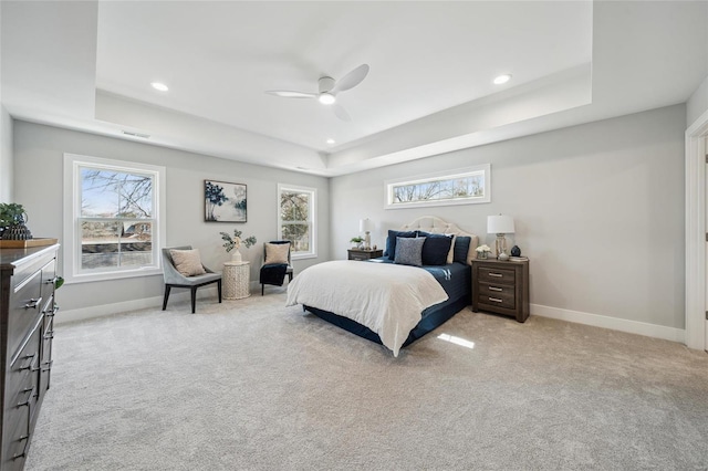 bedroom with a tray ceiling and light colored carpet