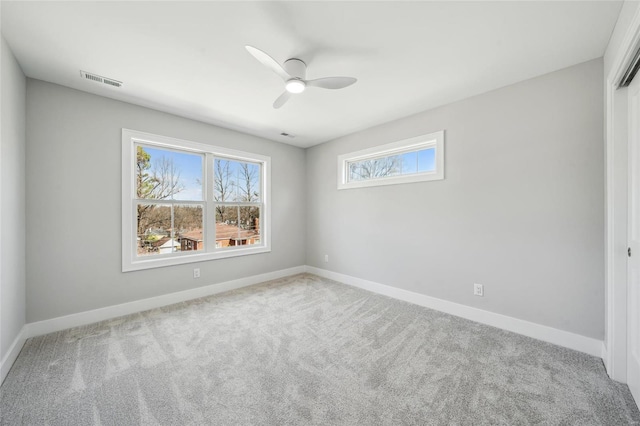 carpeted spare room with visible vents, ceiling fan, and baseboards