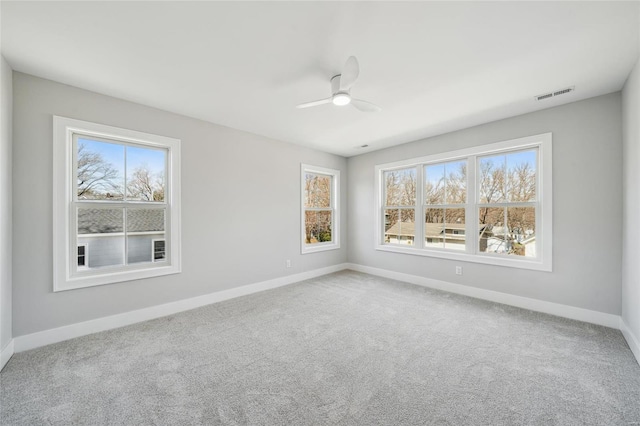 unfurnished room featuring plenty of natural light, baseboards, visible vents, and carpet floors