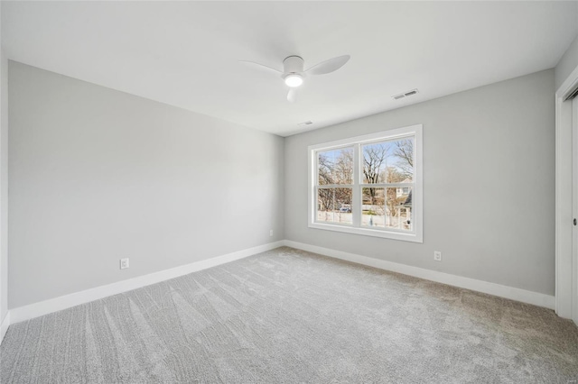 carpeted empty room featuring visible vents, a ceiling fan, and baseboards