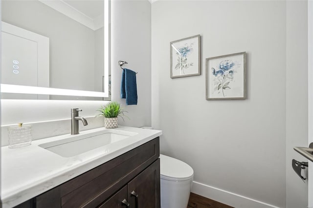 half bath with baseboards, toilet, and vanity