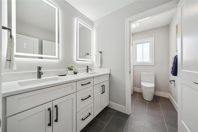 bathroom with a sink, baseboards, double vanity, and tile patterned flooring