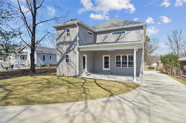 rear view of property featuring entry steps, driveway, a yard, and a patio