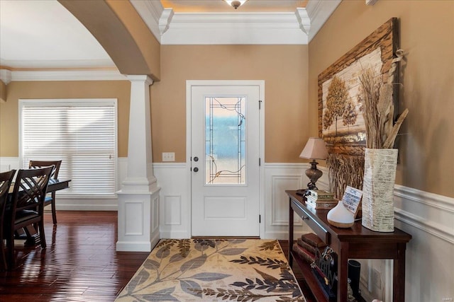 entryway featuring a wainscoted wall, decorative columns, arched walkways, and plenty of natural light