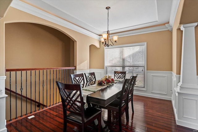 dining space with wood finished floors, an inviting chandelier, decorative columns, ornamental molding, and wainscoting