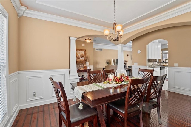 dining space featuring visible vents, dark wood-type flooring, ornamental molding, decorative columns, and arched walkways