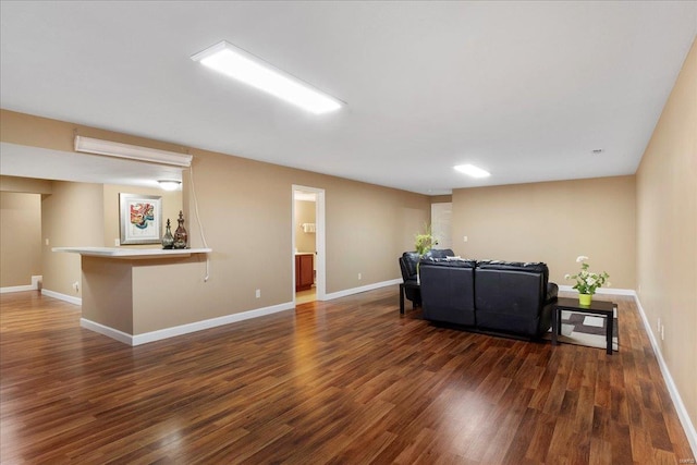 living area featuring baseboards, a bar, and wood finished floors