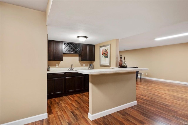 kitchen with a sink, baseboards, dark wood finished floors, and light countertops