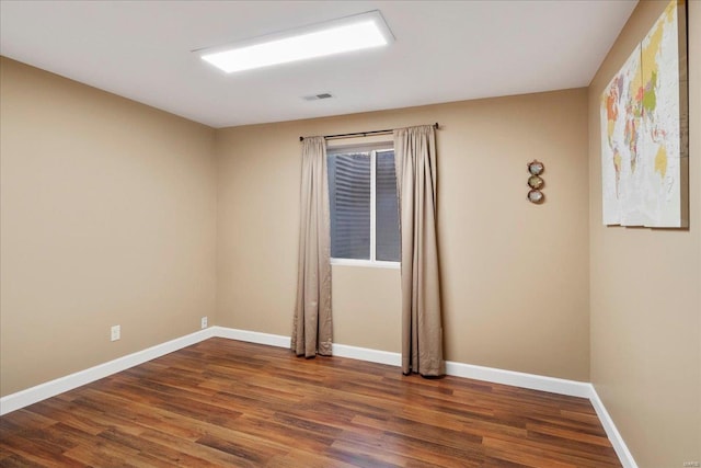 spare room with visible vents, baseboards, and wood finished floors