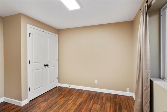 unfurnished bedroom featuring baseboards and dark wood-type flooring