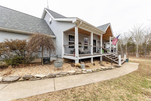 view of side of home with covered porch and a shingled roof