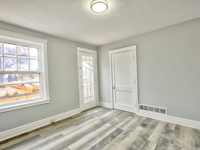 spare room with visible vents, baseboards, and wood finished floors