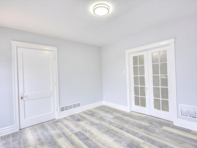 unfurnished room featuring wood finished floors, visible vents, french doors, and baseboards