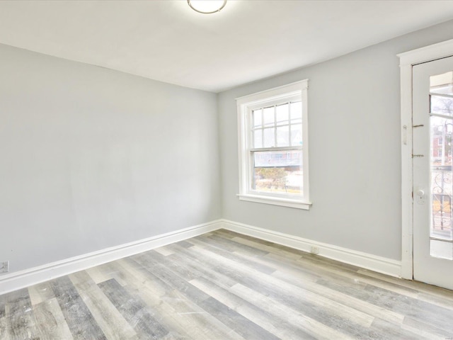 empty room featuring baseboards, a healthy amount of sunlight, and wood finished floors