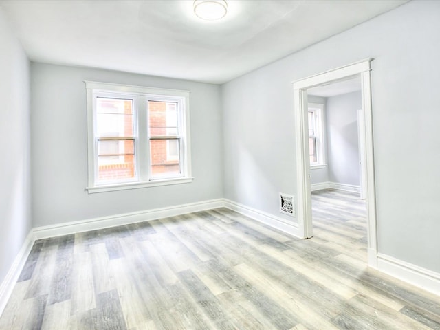 spare room with baseboards and wood finished floors