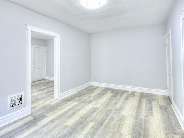 empty room featuring wood finished floors, visible vents, and baseboards