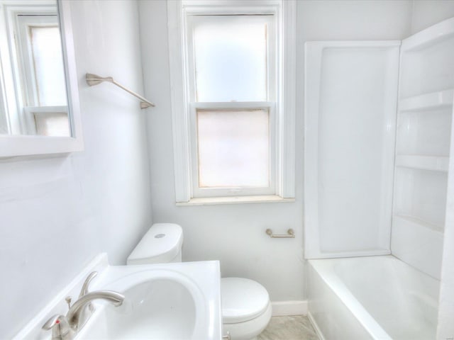 bathroom with toilet, baseboards, and a sink