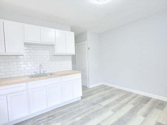 kitchen featuring a sink, light wood-type flooring, backsplash, and butcher block counters