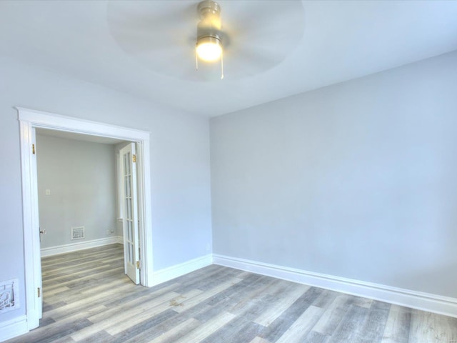 spare room with a ceiling fan, wood finished floors, and baseboards