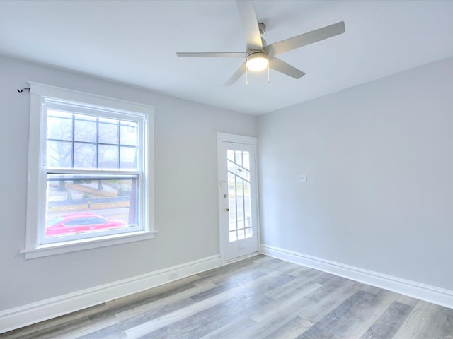 empty room with wood finished floors, baseboards, and ceiling fan