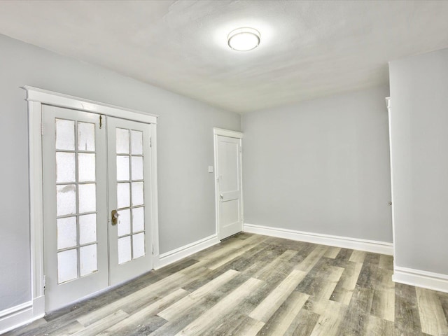 unfurnished room with wood finished floors, french doors, and baseboards