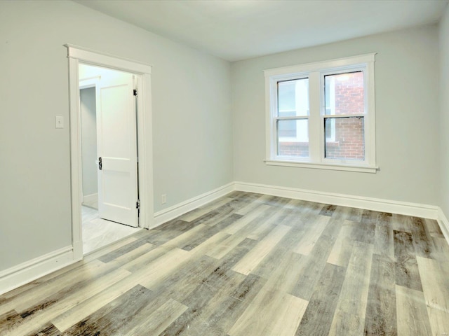 spare room with baseboards and wood finished floors