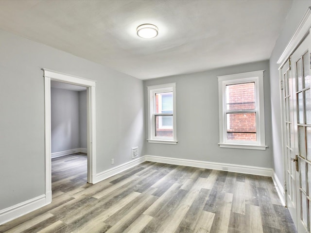 unfurnished room featuring plenty of natural light, baseboards, and wood finished floors