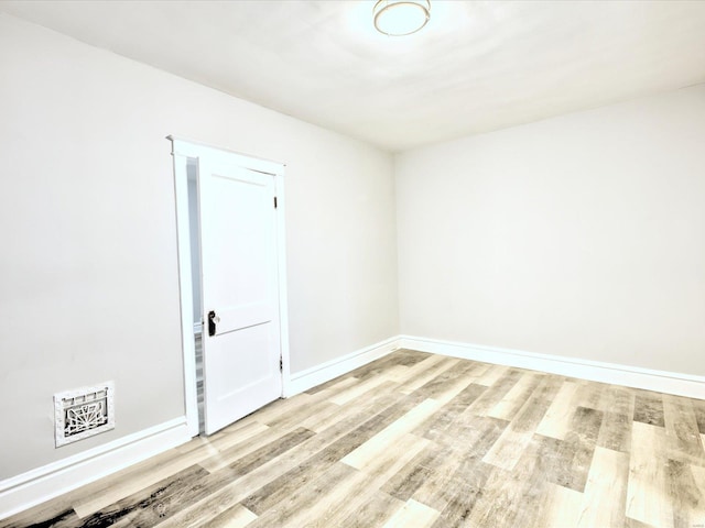 spare room featuring visible vents, baseboards, and wood finished floors